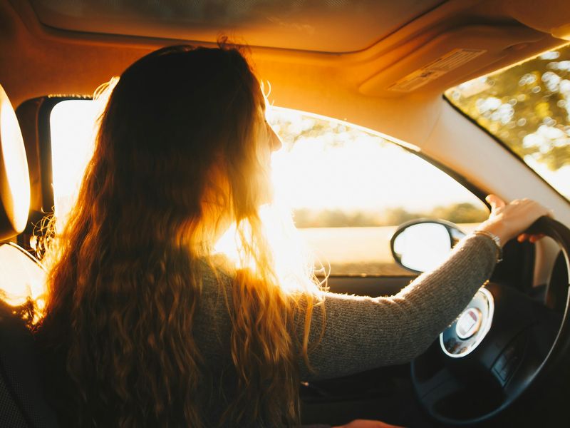 Una conductora joven al volante, con la luz de la tarde.